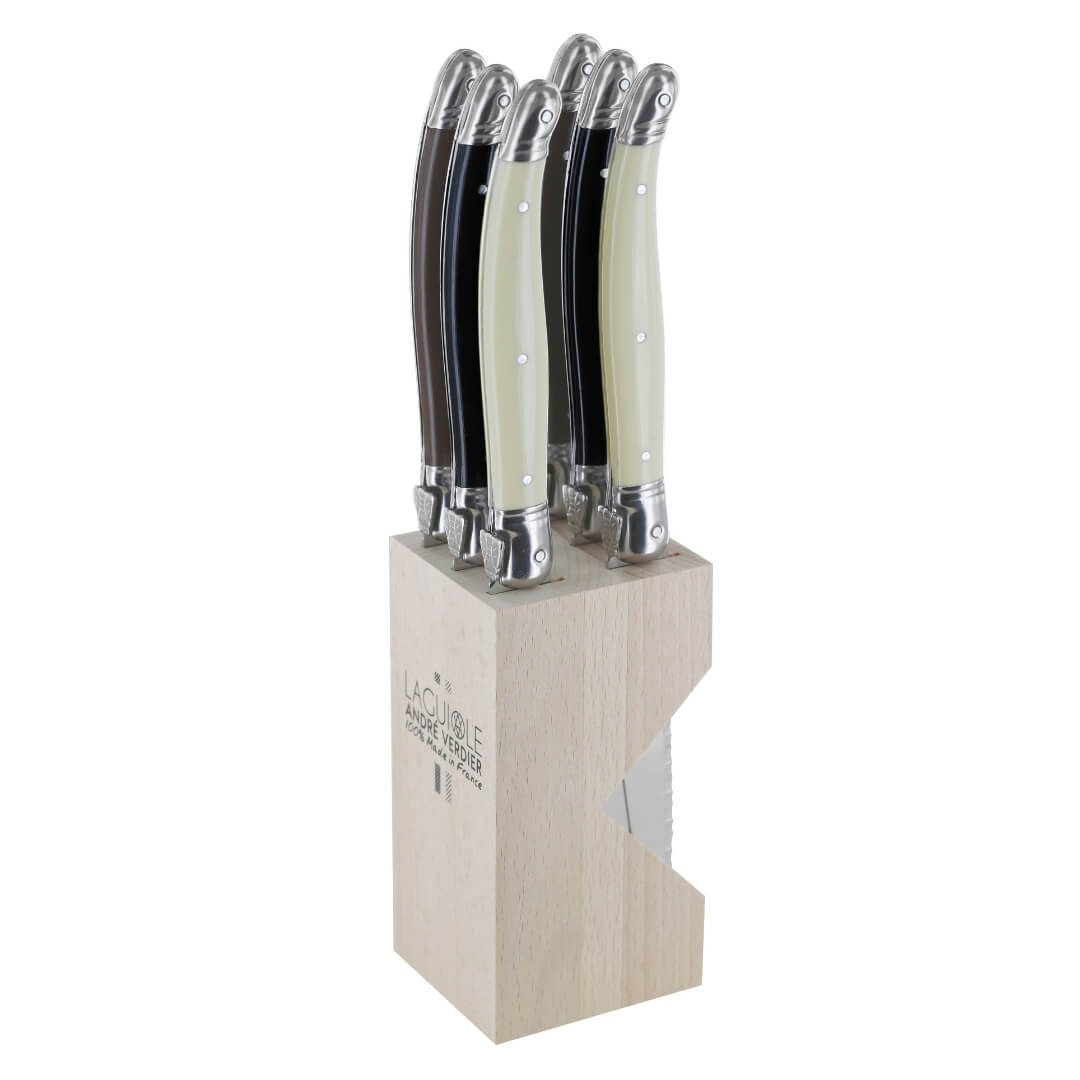 Set of steak knives with resin handles in a wooden block on a white background